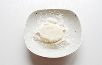 【芝士金枪鱼可乐饼】,盘子中撒适量面粉（手粉），用勺子挖25g左右的土豆泥放在面粉上，手指沾面粉将土豆泥摁成饼状；