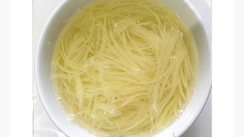 剁椒酸辣土豆丝#食材土豆#,土豆丝用清水浸泡5分钟，避免土豆丝变色。然后捞起沥干水分备用。