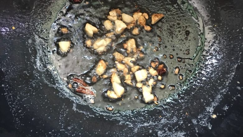 日本豆腐茄子煲,锅内留少许底油,放入蒜瓣:因为炸过,油份比较大,所以不用放太多的油。