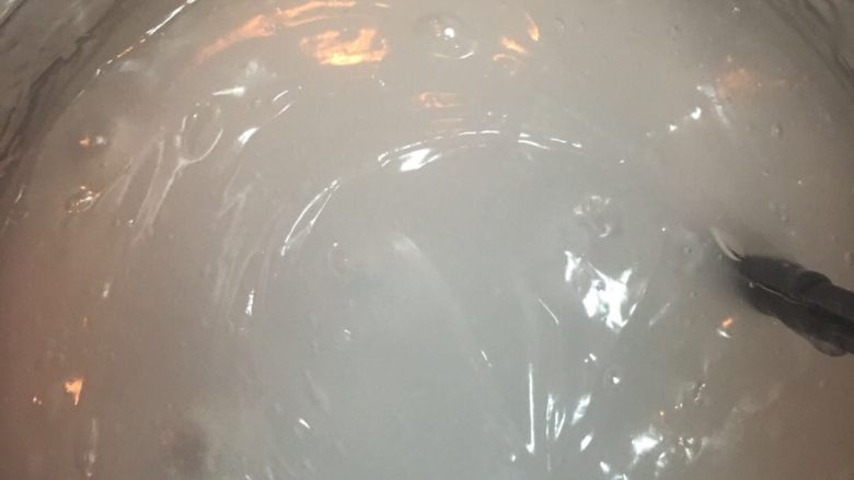 自制凉粉,水开后把调匀的碗豆粉浆倒进去,细长流慢慢倒进去。一边倒一边搅锅,以免起疙瘩。烧开后,调成小火不断的煮,煮成半透明的,煮的白色越少越好。
备注:实在怕疙瘩的话不用等水开再倒,水热稍冒白烟就可以把粉浆倒进去。倒的方法一样。