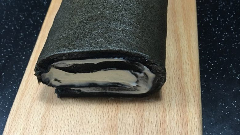 黑白蛋糕卷(竹炭卷),在蛋糕片上均匀涂抹淡奶油,卷的前部稍厚一些,尾部留二三厘米不要涂抹.可借助擀面杖将烘焙纸后卷在擀面杖上,慢慢卷起