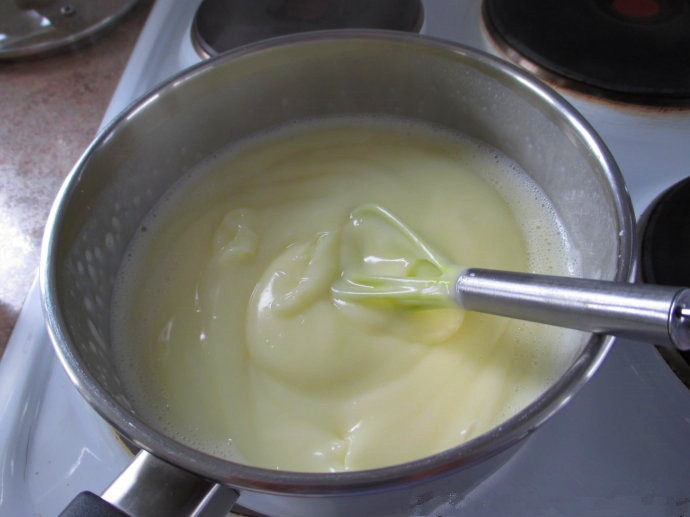 香草卡仕达方块——Vanilla Custard Squares ,往牛奶里加入卡仕达混合物,用打蛋器快速搅拌,直至卡仕达变浓稠,离火,加入香草精,搅拌均匀