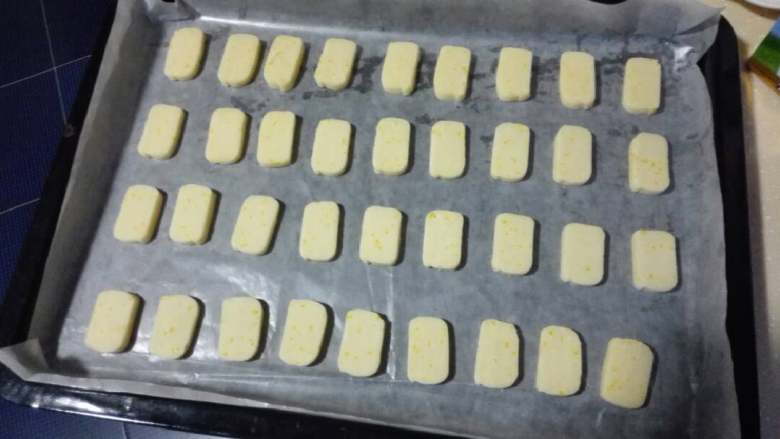 清香柠檬饼干,烤箱170度预热10分钟。取出面团,切成0.4mm厚的块,排入烤盘中,入烤箱中层,15分钟左右取出放凉。