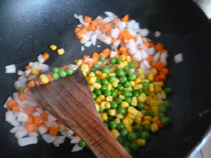 鲑鱼炒饭~~剩米饭的美丽转身,锅里下少许油烧热后下洋葱煸炒至微透明下青豆玉米胡萝卜,入少许盐调味,盛出。