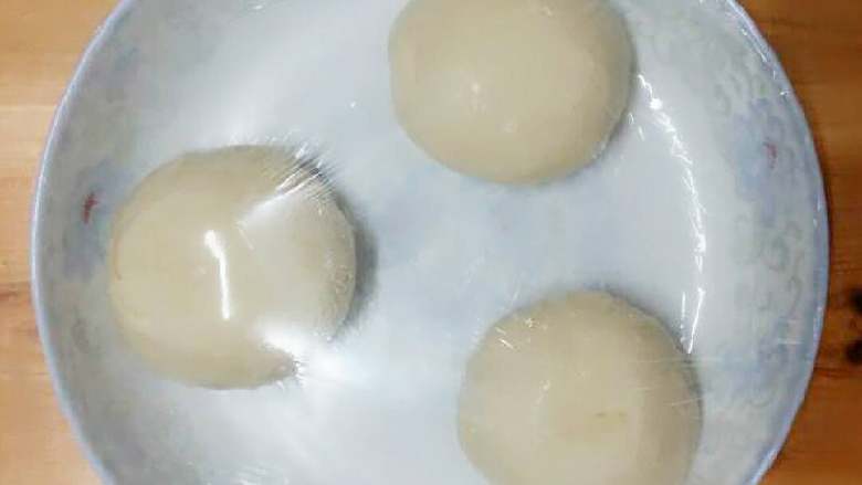 鸡油葱香手抓饼,再揉面团,分成三个剂子摸上油,揉圆放入抹过油的盘中,盖上保鲜膜放到温暖的地方醒面。