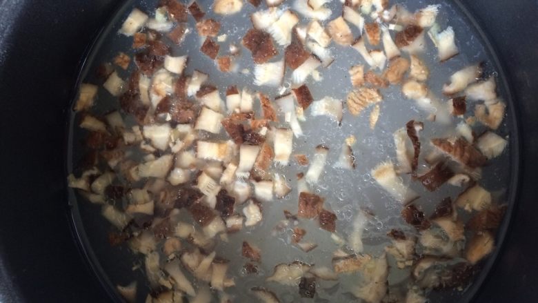 香菇滑肉粥,待锅中大米煮沸,放入香菇跟姜末一起煮至粥软糯黏稠