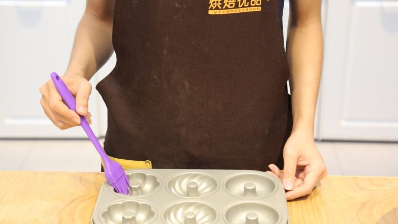烤箱版#巧克力甜甜圈,在模具中刷一层黄油,方便脱模