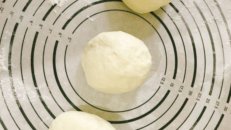 像棉花糖一样柔软的牛奶吐司,排气好了之后分成三等份，依次揉圆，盖上保鲜膜醒发一刻钟。揉面垫上可以撒适量高筋面粉，防止面团黏着。