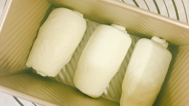 像棉花糖一样柔软的牛奶吐司,重复上面的步骤，二次醒发好之后，擀成长舌状然后卷起来放入吐司模具内，中间留有空隙，放入烤箱发酵四十分钟左右；也可以室温发酵，发到八分满左右！