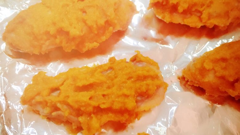 美味烤鸡翅——【牛奶苹果咖喱酱版】,把鸡翅洗净用料理纸擦干抹上做好的咖喱酱料，盛到碗里放入冰箱腌制一小时以上，但不要腌时间过久超过24小时以免影响味道，然后拿出，依然带着酱料不要刮掉，铺好锡纸准备好