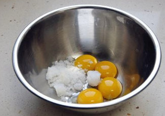 【红枣黑芝麻蛋糕卷】,蛋黄中加入棉白糖,用打蛋器搅打至混合均匀。