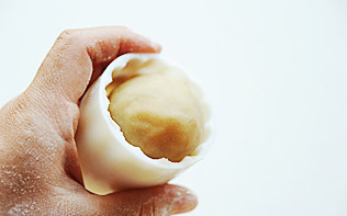 白莲蛋黄月饼,将月饼胚子滚成长椭圆,放进月饼模子里,在撒了薄薄的面粉的案板上用力压模具,然后提起;