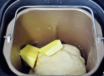 【酒香核桃面包】,揉成光滑面团后加入b.黄油继续揉面。