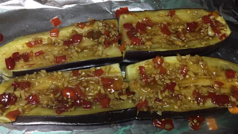 香烤茄子,将炒好的调料涂在茄子上,为了更入味,可以在茄子上划些口