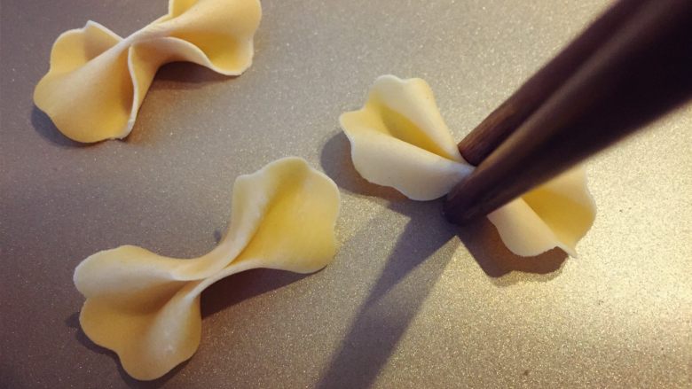 缤纷手工营养面-让宝贝快乐成长的健康辅食,上面是蝴蝶面的做法,先用模具压扣出造型,然后用筷子从中间夹一下