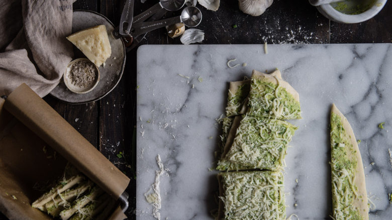  芝士蒜香手撕面包,将配料中的黄油、大蒜碎、欧芹碎、大蒜粉搅拌均匀。将发酵好的面团擀成25*35cm的长方形，将刚才调好的香料黄油均匀抹在面团上，撒上三种奶酪(不用都撒完)，再将面条切成小块。