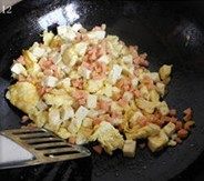 蛋包豆腐丁 ,等豆腐快出锅时,可加入少量火腿丁翻炒,中和味道,关火出锅盛盘,撒少许香葱,调节颜色,看起来更加有食欲。