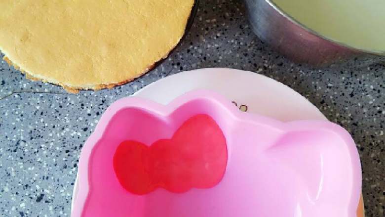 Hello Kitty 奶酪蛋糕,牛奶溶液一点点加入奶酪糊中,拌匀,然后用勺子舀出两勺分别调成粉红和黄色,红色放入蝴蝶结中,黄色加入鼻子中,放入冰箱冷冻十分钟
