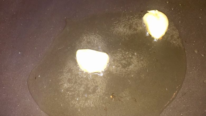 黑椒白芦笋炒牛柳,将蒜瓣去衣拍开,放入发白烟油锅中煎至略焦捞起。
