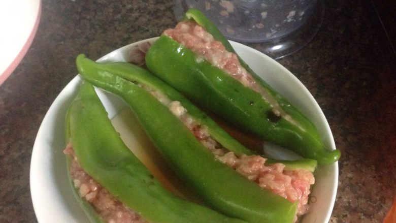 虎皮椒酿肉,接着就把腌制好的肉放入虎皮椒肚子内,摆好后加入适量的矿泉水和酱油