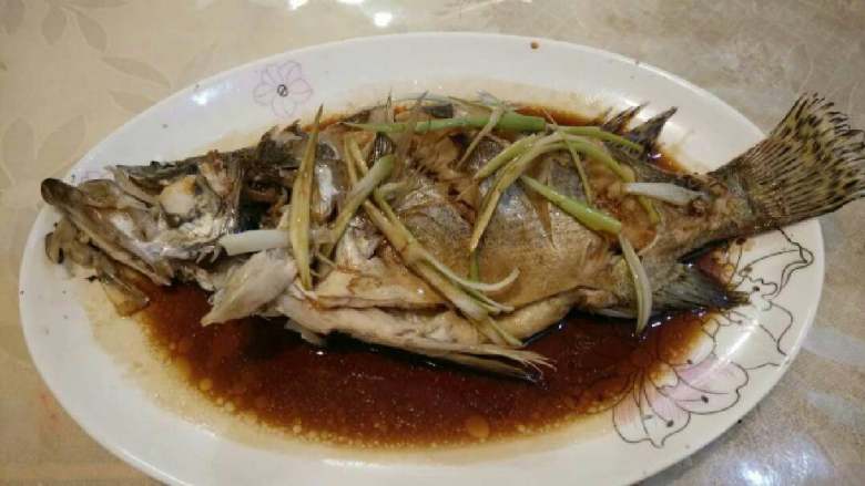 清蒸鲈鱼,端出后，倒掉盘里的水，蒸过的姜大葱丢弃不用，铺上葱丝儿，淋上<a style='color:red;display:inline-block;' href='/shicai/ 864'>蒸鱼豉油</a>