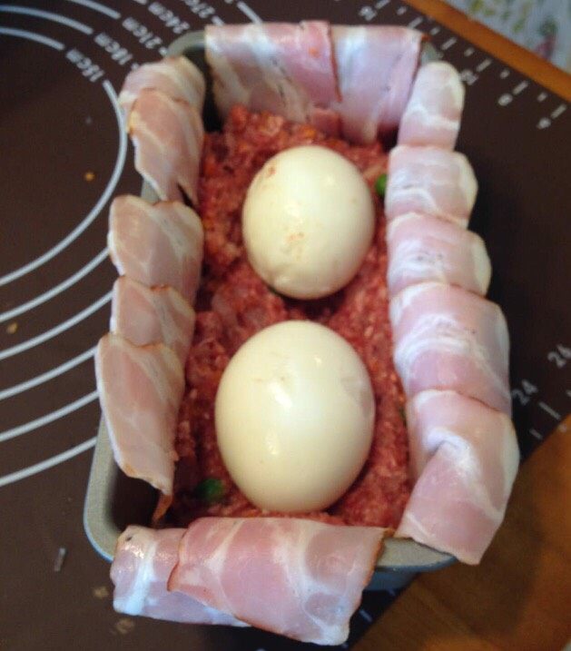 培根肉卷,把混搅好的肉沫的一半放在盒底,并放上煮好的鸡蛋