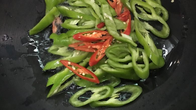 #年夜饭#黑胡椒爆猪心,锅内放入少许的油加热,倒入切好的青椒红椒片,高火快炒几下。