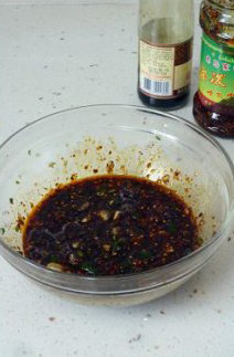 【凉拌酸辣黑啤猪蹄】,大蒜夹成蒜泥,青椒切碎后放入碗中,再倒入油泼辣子、凉拌汁、蜂蜜醋拌匀。
