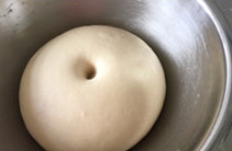 茄丁酱肉包,当面团变大约原来的两倍,手指戳入面团不回缩即发酵完成后取出并拍扁面团,案板上撒上约三五十克面粉(配方外的)后,再次将面团揉光滑后,表面覆盖湿布或是保鲜膜静置5分钟。