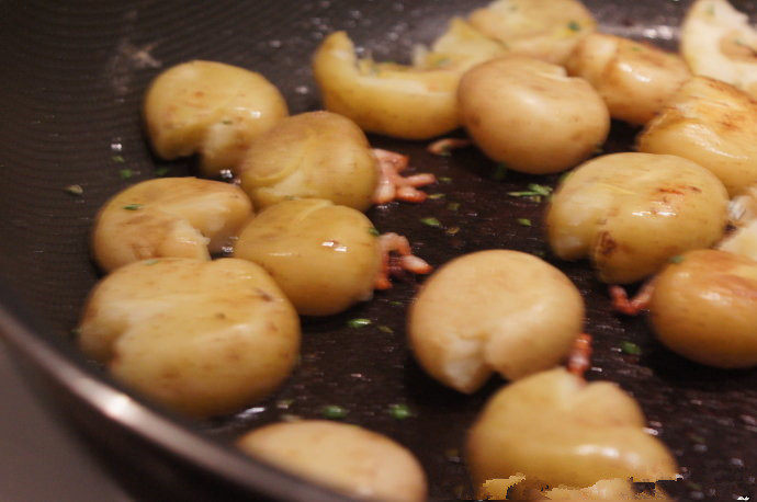 培根迷迭香小土豆,倒入土豆，用勺子轻压扁土豆，撒入迷迭香，慢慢将土豆两面煎至金黄，撒上海盐和黑胡椒即可