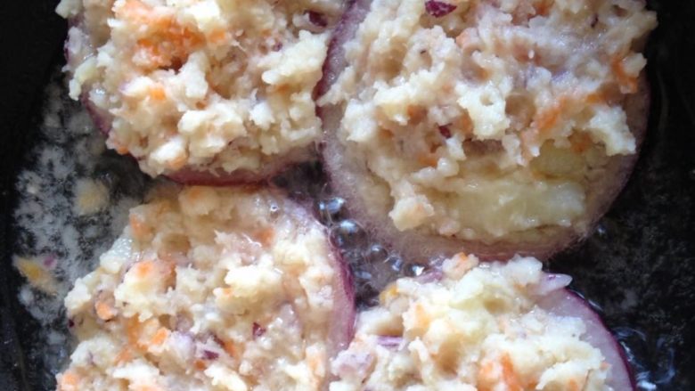 洋葱土豆圈,舀土豆泥蛋糊放入洋葱圈内，小火煎至定型，翻转另外一面至两面都金黄，盛出装盘。