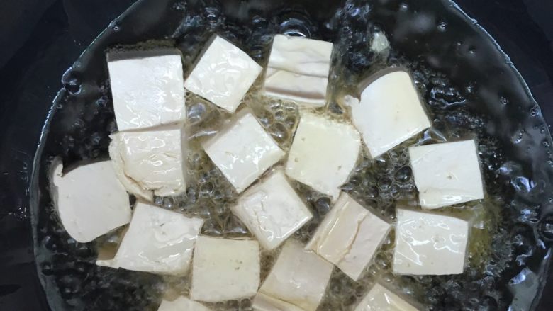 韭苔炒豆腐,油温加热至八成热,将豆腐块逐一放入锅中。