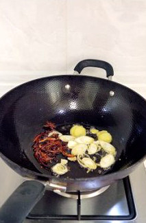 经典家常菜干豆角红烧肉,锅中油热放入花椒、八角、干辣椒丝，煸炒至辣椒颜色变深，然后再放葱、姜炒香。