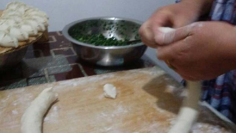 蓬莱饺子,面再次揉一揉,从中间开洞不停一个方向双手交替捏后,断开滚到合适粗细用手拽出均匀剂子,撒上面粉滚圆按扁。(一般肉多剂小点,菜多大点能包进菜)