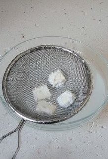 将牛轧糖滚成汤圆 ,拿出放筛子中轻轻喷水一层,或者快速的过下碗里的水。