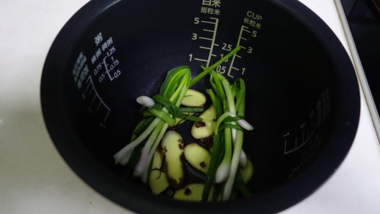 电饭煲版盐焗鸡,电饭锅底铺上姜片,放两把葱,撒几颗<a style='color:red;display:inline-block;' href='/shicai/ 700'>花椒</a>,舀一勺食用油,又不用太多,可以不放,因为在焗的过程中会有鸡油滴落,不用担心锅会烧焦