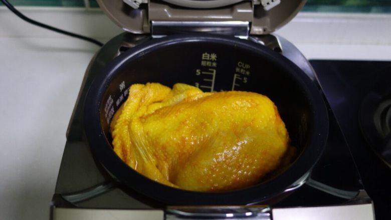 电饭煲版盐焗鸡,腌制好的鸡正面放入锅中,启动正常煮饭程序