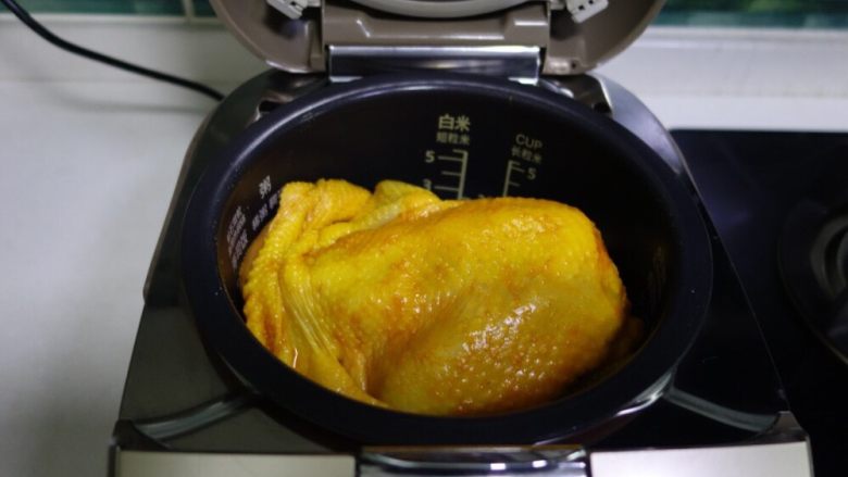 电饭煲版盐焗鸡,腌制好的鸡正面放入锅中，启动正常煮饭程序