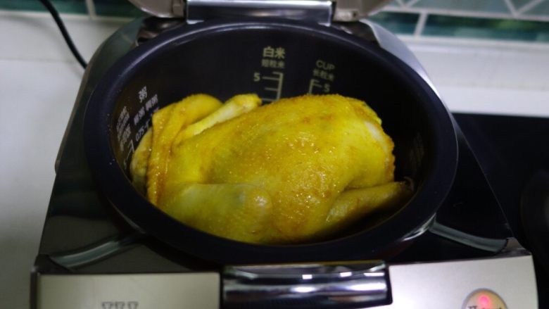 电饭煲版盐焗鸡,时间到,哇哦,黄灿灿的真漂亮,这个时候千万不要心急哦,将鸡翻个面,让鸡的背部接触锅里的盐焗鸡料,再按煮饭键,继续焗8分钟左右