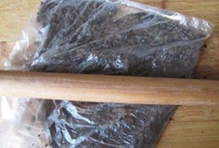 重口味来袭----榴莲芝士蛋糕,将饼干装入保鲜袋中, 用擀面杖碾碎;