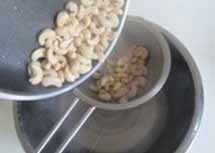 自制健康小零食--芝麻腰果,锅中放入适量的油, 将焯过水的腰果放入里面, 倒入适量的油,不停地翻炒;
