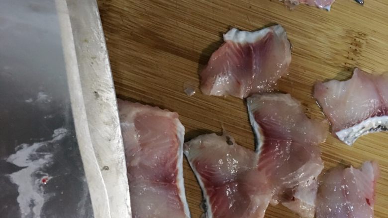 自制酸菜鱼,两两块鱼肉按斜刀方式改刀片鱼片,鱼骨剁段备用。