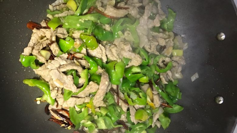 家常小炒肉,将青辣椒、碗中炒好的肉,淋一点麻椒油放入锅内翻炒1-2分钟