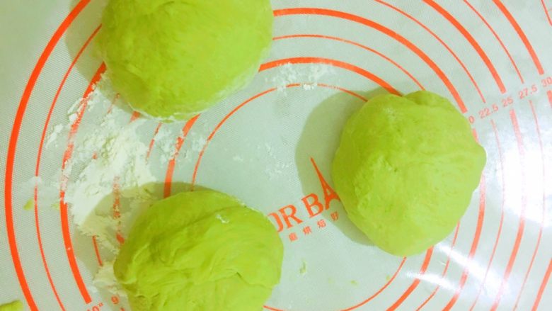 像月牙一般温柔的抹茶红豆软欧包,取出面团排气,排好气之后分成三等份,依次揉圆,盖上保鲜膜醒发一刻钟。揉面垫上可以撒适量高筋面粉,防止面团黏着。