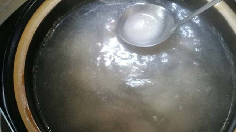 萝卜炖排骨,沙锅内排骨后,用勺子去除血膜。