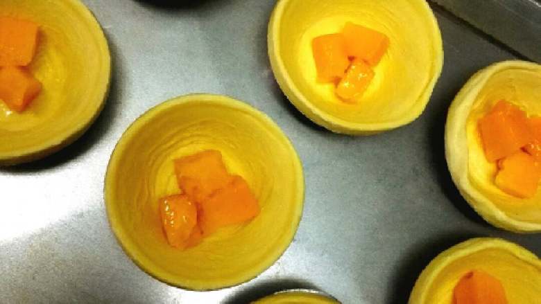 果味蛋挞#挑战鸡蛋的100种做法#,放入解冻好的蛋挞皮里，一个里面只要没两三个芒果粒就可以了