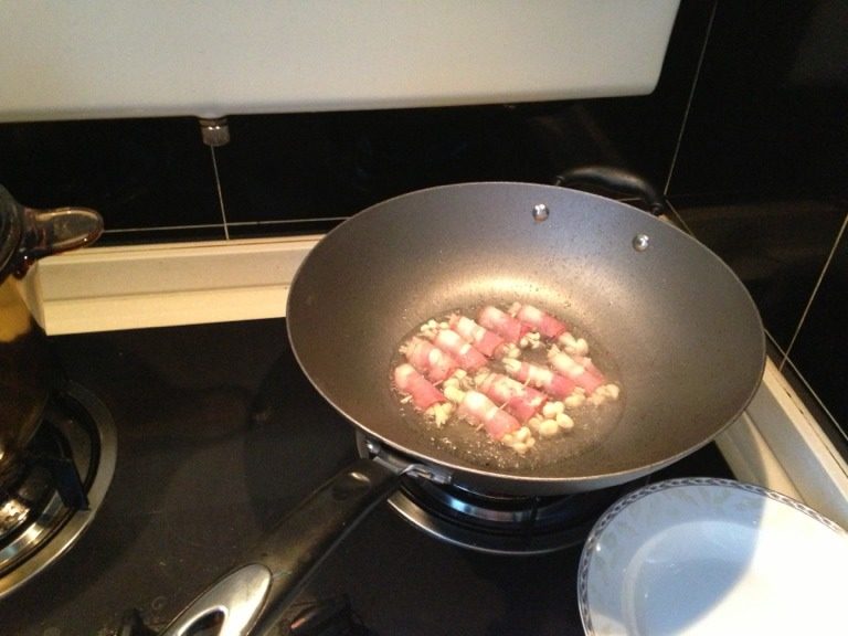 金针培根卷,锅中放少量油，油温五成热，下培根卷，小火慢煎，煎至金黄色即可。