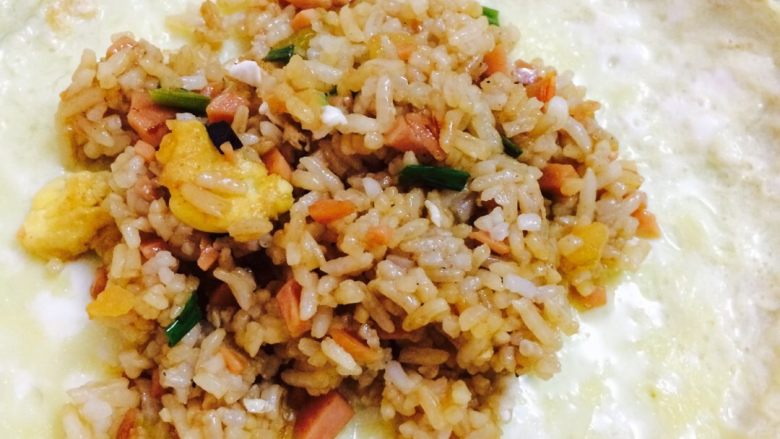 蛋包饭#挑战鸡蛋的100种做法#,把炒好的饭放在蛋皮的中间(炒饭的步骤省去了,已经写有炒饭的菜晋了)压实炒饭,先把两头的折回来,再把两边的包起来,口向下放