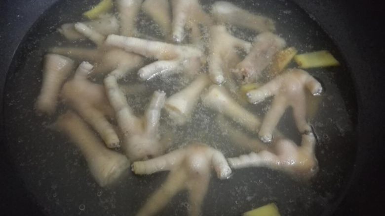 虎皮鸡爪,鸡爪放姜片还有料酒一起焯水。焯水之后就过冷水之后就捞起来等它表面的水放干,或者用厨房纸垫底吸水吸干。