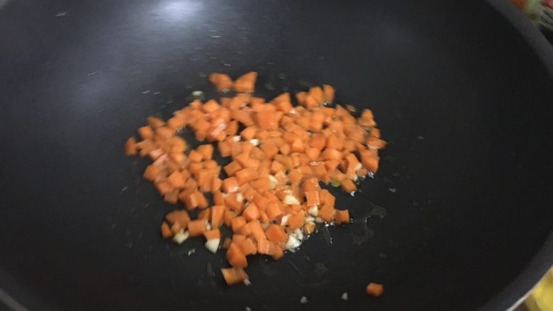 黄金蛋炒饭,热锅热油放点蒜蓉,然后放胡萝卜翻炒。炒到七成熟就放火腿芹菜翻炒。记得放点盐。